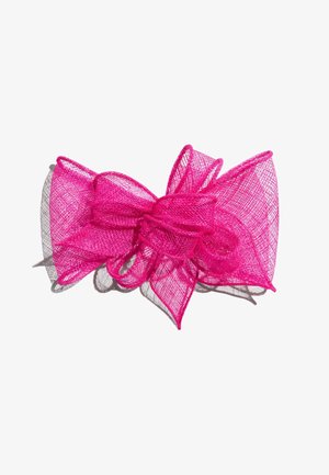 Lyserød dekorativ net sløjfe med flere løkker og spidse kanter, der kaster en skygge på en hvid baggrund.