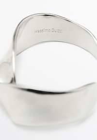 Zilveren metalen manchetarmband met een glad, gebogen ontwerp. Gegraveerd met "Massimo Dutti" aan de binnenkant, met een gepolijste afwerking.