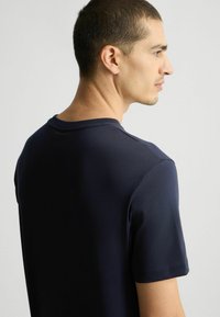 Maglietta a maniche corte blu navy realizzata in morbido cotone; presenta un classico colletto a girocollo e dettagli di cucitura minimi.