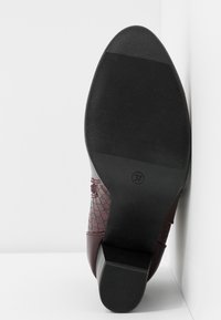 Botte en cuir bordeaux avec un motif croco texturé, dotée d'une semelle et d'un talon en caoutchouc noir, taille 37, inclinée sur un fond blanc.