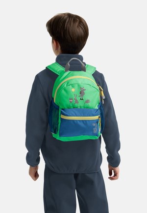 Bambino con uno zaino verde e blu con illustrazioni di animali, visto di spalle, vestito con una giacca in pile scura e pantaloni.
