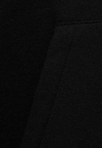 Gros plan sur un tissu noir avec des coutures visibles et un motif tricoté texturé.