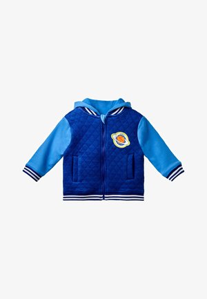 Mėlynas siuvinėtas švarkas su mėlynomis rankovėmis. Yra dryžuotas ribotas kraštas ir rankogaliai, priekiniai kišeniai ir apskritas planetos piešinys ant krūtinės.