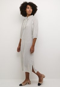 Robe midi rayée en tissu léger, avec un col à rabat orné de volants et des manches 3/4 ; les fentes latérales améliorent le mouvement.