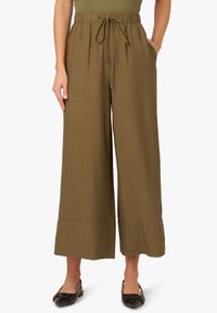 Pantalons larges de couleur olive en tissu texturé. Dotés d'une taille élastique avec cordon de serrage et de poches latérales. Ourlet plat.