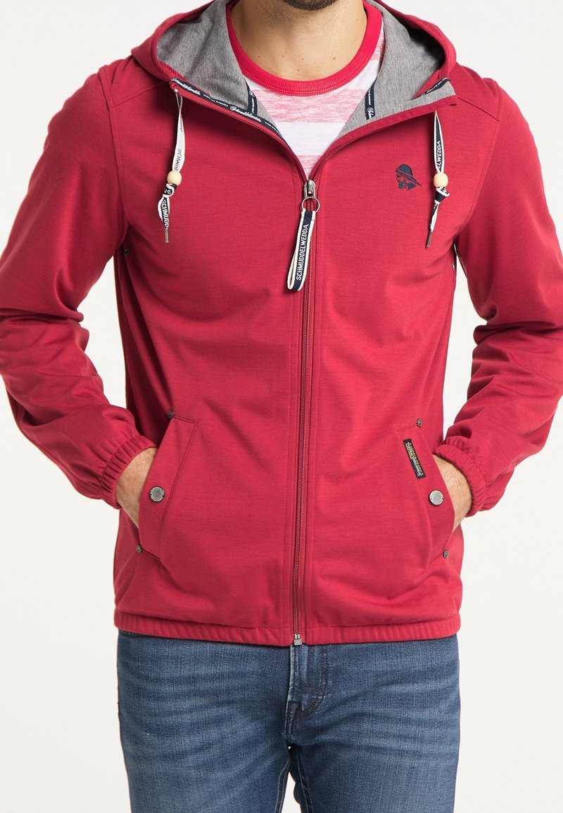 Veste zippée rouge avec doublure de capuche grise, cordons de serrage ajustables, poches avant et poignets élastiques. Texture lisse et design moderne.