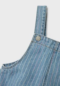 Jeansoveraller i vertikala blå och rosa ränder, justerbara axelremmar och en metallspänne upptill.