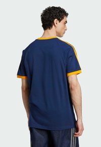 Navy blue t-shirt with yellow trim on the sleeves and neckline. Soft, smooth fabric, relaxed fit, and a round neckline.