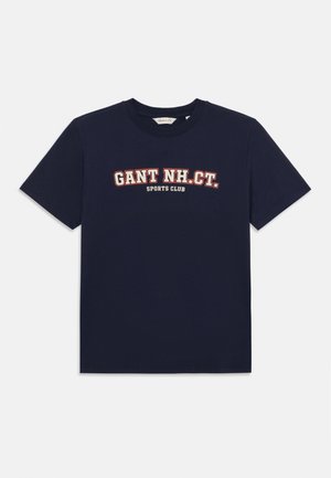 Navy blue cotton t-shirt with short sleeves, featuring a white and red graphic text "GANT NH. CT. SPORTS CLUB" on the front.
