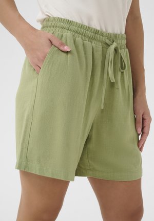 Shorts à taille élastique vert clair avec cordon de serrage, poches latérales et tissu texturé. L'ourlet arrive à mi-cuisse. Design simple et fonctionnel.