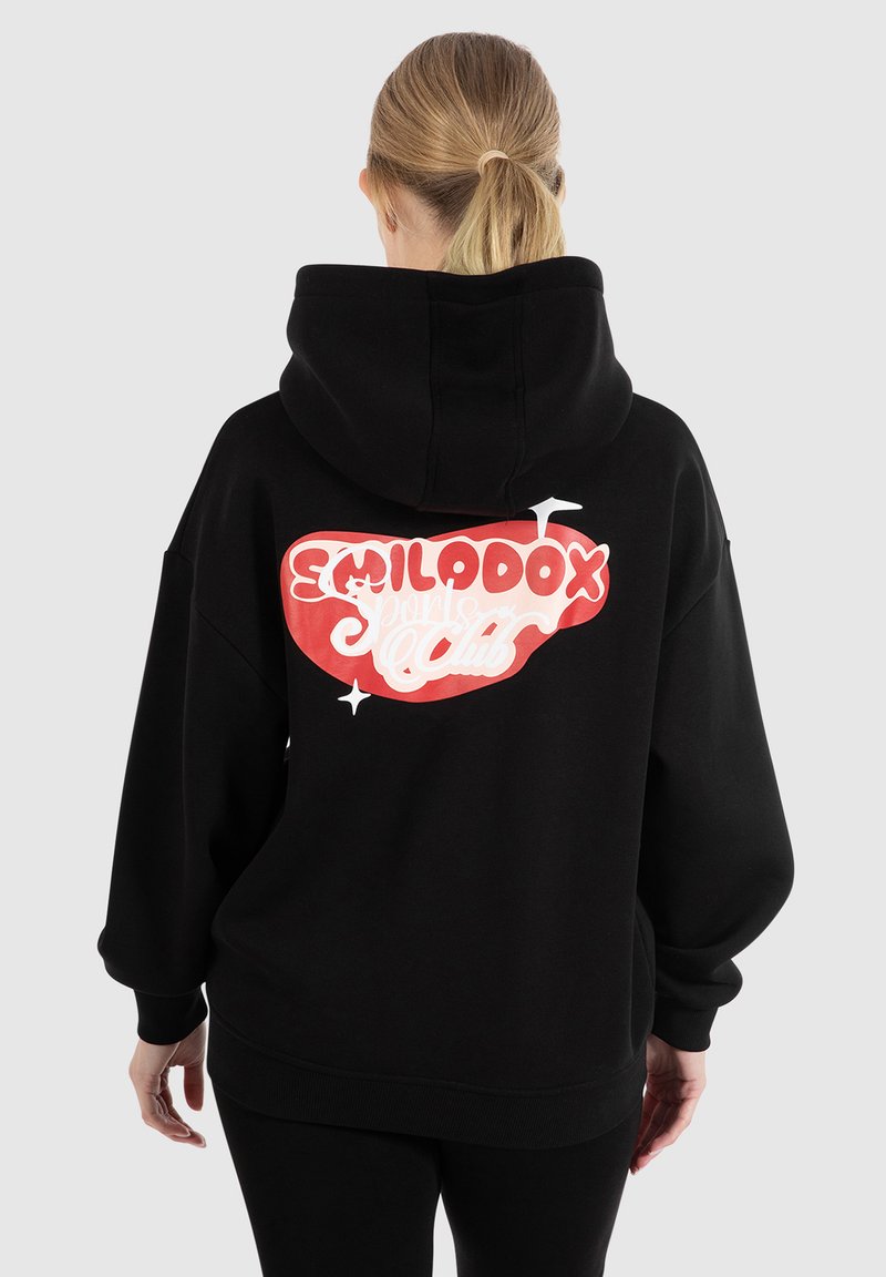 Hoodie noir avec un grand graphique "SMILADOX" rouge et blanc au dos. Coupe ample avec une capuche spacieuse et des poignets côtelés.