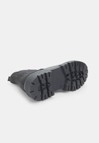 Cizma ankle neagră cu un superior textil texturat și talpă din cauciuc cu un model. Dispune de un profil robust pentru aderență și o bucată de țesătură pentru a fi ușor de încălțat.