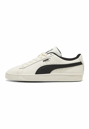 Witte Puma Suede sneaker met zwarte logostreep, veterontwerp en gestructureerde zool, zijaanzicht op een witte achtergrond.