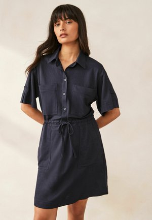 Marineblaues kurzärmliges Hemdkleid aus leichtem Stoff mit Knopfleiste, zwei Brusttaschen und einer Zugbandtaille für eine lockere Passform.