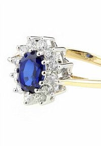 Anello in oro e argento con un centro di zaffiro blu ovale circondato da piccoli diamanti bianchi rotondi, con una finitura lucida.
