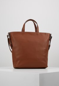 Sac fourre-tout en cuir marron avec une finition texturée, doté de deux poignées supérieures et d'une bandoulière amovible. Design minimaliste et forme élégante.