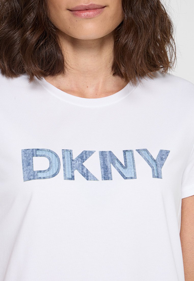 Camiseta de algodón blanca con un gráfico de "DKNY" en textura de denim azul en el pecho. De mangas cortas y con un escote redondo.