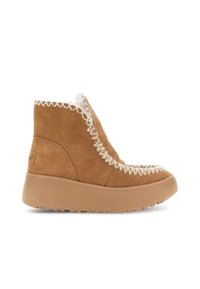 Béžové semišové kotníkové boty s tlustou gumovou podrážkou, bílou kožešinovou podšívkou a dekorativním cik-cak prošíváním kolem okrajů.