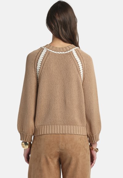 Pulover maro tricotat, cu tiv dantelat, mâneci tip balon și accente decorative din dantelă albă pe umeri și la decolteu.