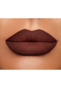 La couleur des lèvres mate dans des teintes brunes profondes couvre entièrement les lèvres ; texture lisse avec des bords bien définis. Le teint de la peau contraste avec la couleur des lèvres pour faire ressortir l'ensemble.