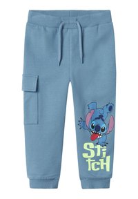 Pantalons de jogging bleu clair en coton doux avec taille élastique, poche avant et impression du personnage Stitch sur la jambe gauche dans des couleurs vives.