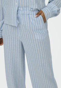 Lichtblauwe gestreepte broek van een zachte stof, met een elastische tailleband en zijzakken, met verticale witte strepen voor contrast.