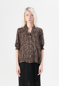 Bluza s leopard uzorkom u smešim i crnoj boji, s kragnom, dugmadi sprijeda i naboranim rukavima. Mekani, lagani materijal.