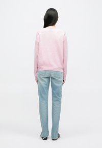 Sweatshirt roz deschis cu guler rotund și tiv ondulat, asortat cu blugi albaștri deschiși. Textură netedă, croială lejeră și detalii minime.