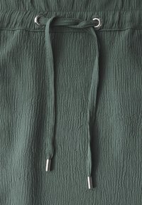 Getextureerde donkergroene stof met een gekreukt ontwerp, voorzien van een trekkoordsluiting en metalen aglet-einden.