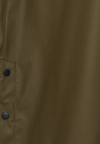 Țesătură de culoare verde măslinie, cu textură netedă și o ușoară strălucire, având nasturi snap negri pe margine și un design minimalist.
