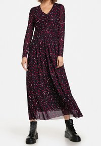 Langarm zwart jurkje met roze en witte abstracte patronen, met een verzamelde taille en een vloeiende rok. Gedragen met zwarte plateau laarzen.