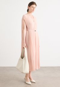 Pleated, pale pink dress with a v-neck and fitted waist, paired with a light beige handbag and pale pointed heels. Simple, elegant design.