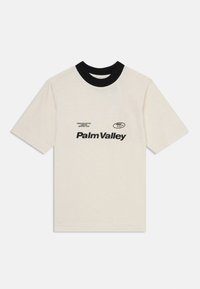 Short-sleeve beige cotton t-shirt with a black ribbed collar and black printed text reading "Palm Valley" on the front.