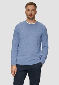 Niebieski sweter z dzianiny z okrągłym dekoltem i ściągaczami. Materiał ma teksturowany wzór, zestawiony z ciemnonawigacyjnymi spodniami.