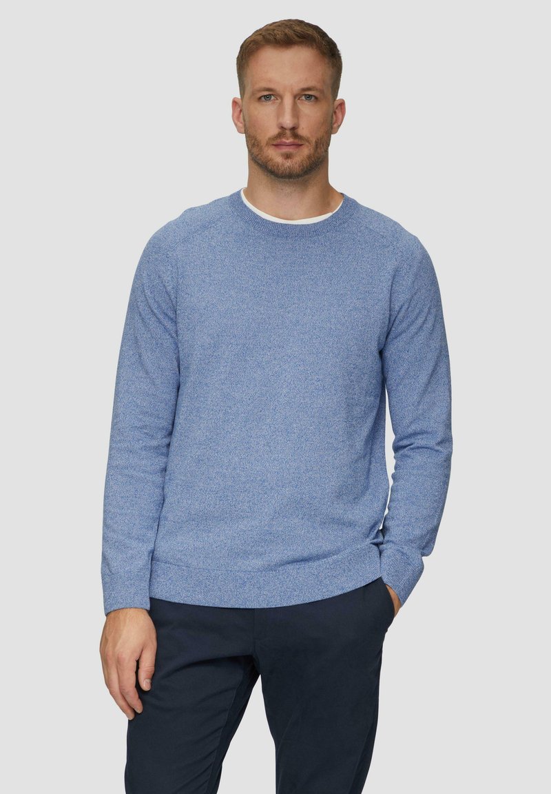 Niebieski sweter z dzianiny z okrągłym dekoltem i ściągaczami. Materiał ma teksturowany wzór, zestawiony z ciemnonawigacyjnymi spodniami.