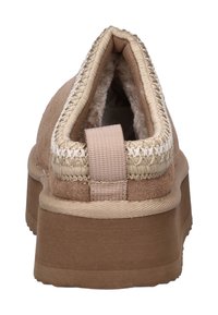 Chausson en suède beige à enfiler avec une semelle en caoutchouc épaisse, doublure intérieure rembourrée et tirant en tissu au niveau du talon, vu de l'arrière.