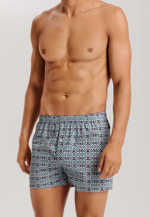 Pantaloni boxer in tessuto blu chiaro con intricati motivi geometrici in blu scuro e verde. Vita elastica per una vestibilità comoda.