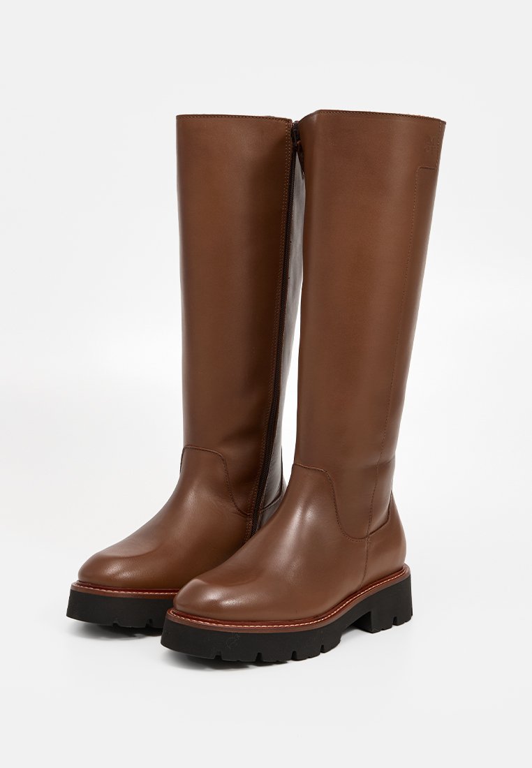 Braune Leder-Knöchelstiefel bis zum Knie mit einer dicken schwarzen Sohle, seitlichem Reißverschluss und glatter Textur, ausgestattet mit einer abgerundeten Zehenpartie und minimalistischem Design.