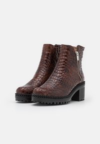 Brown leather ankle boots with a textured snake pattern, side zipper, block heel, and a black rubber sole with braided accents.