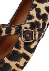 Zapato plano con estampado de leopardo y parte superior de piel texturizada, con una correa negra y una hebilla cuadrada de latón antiguo. Interior de cuero marrón.