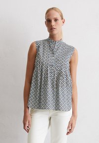 Ärmellose Bluse in Hellblau mit einem geometrischen Muster in Gelb und Marineblau. Sie hat einen Stehkragen und eine Knopfleiste vorne.