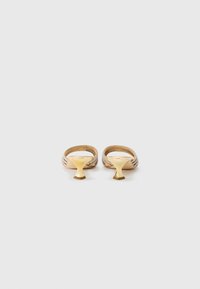 Mules à talons beiges avec un design tissé et un talon sculpté doré. Texture lisse avec un dos ouvert, affichant une esthétique minimaliste.