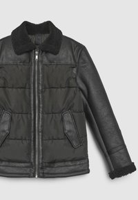 Doudoune noire avec manches en cuir et col duveteux, dotée d'une fermeture éclair et de deux poches latérales à finition texturée.