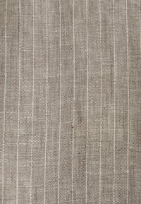 Tissu beige tissé avec de fines rayures blanches verticales, espacées de manière régulière, et une surface texturée légèrement rugueuse.