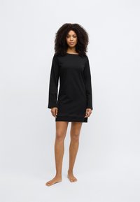 Črna obleka z dolgimi rokavi in ravnim krojem, izdelana iz mehke tkanine, z okroglim izrezom in detajli na spodnjem robu.