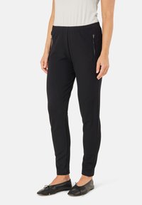 Zwarte sportbroek met een aansluitende pasvorm, elastische tailleband en zijzakken met rits. Gemaakt van een gladde, rekbare stof.