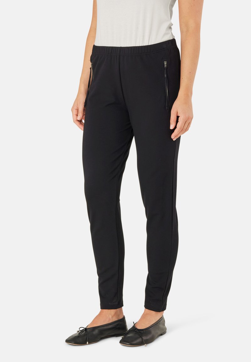 Zwarte sportbroek met een aansluitende pasvorm, elastische tailleband en zijzakken met rits. Gemaakt van een gladde, rekbare stof.