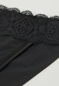 Zwart kanten bodysuit met ingewikkelde bloempatronen aan de bovenkant, een gladde textuur op het lichaam en elastische afwerking langs de randen.