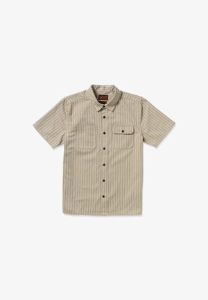 Beige T-shirt met korte mouwen en zwarte verticale strepen, twee borstzakken, een puntige kraag en een sluiting met knopen aan de voorkant. Glad textuur van de stof.