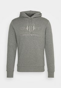 Gray hoodie made of soft fabric, featuring a front pocket and drawstrings. The design includes an embroidered logo and year on the chest.
